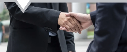 Two young businessmen shaking hands over business deal with div