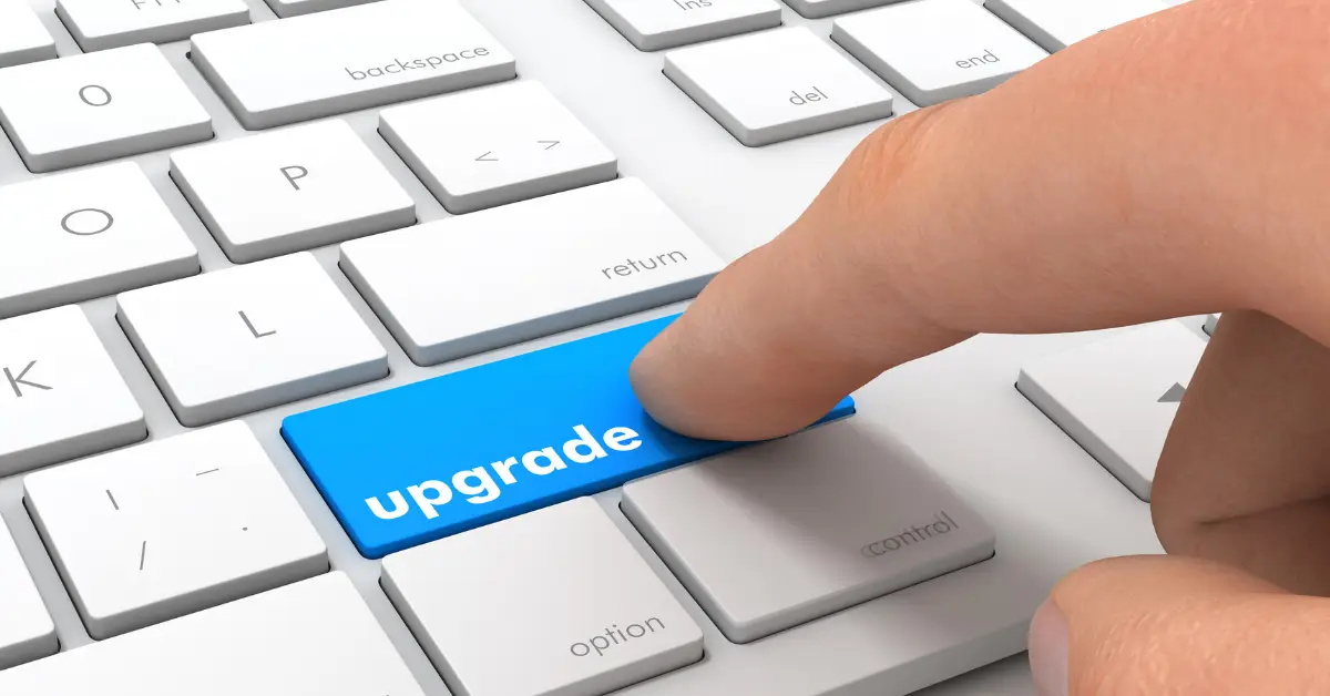 Finger pressing a blue 'upgrade' key on a white computer keyboard